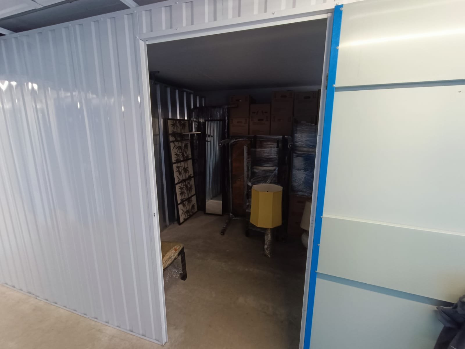 Innenbereich der Lagerbox vor der Entrümpelung – Kartons, Möbel und Lampen gestapelt bis zur Rückwand